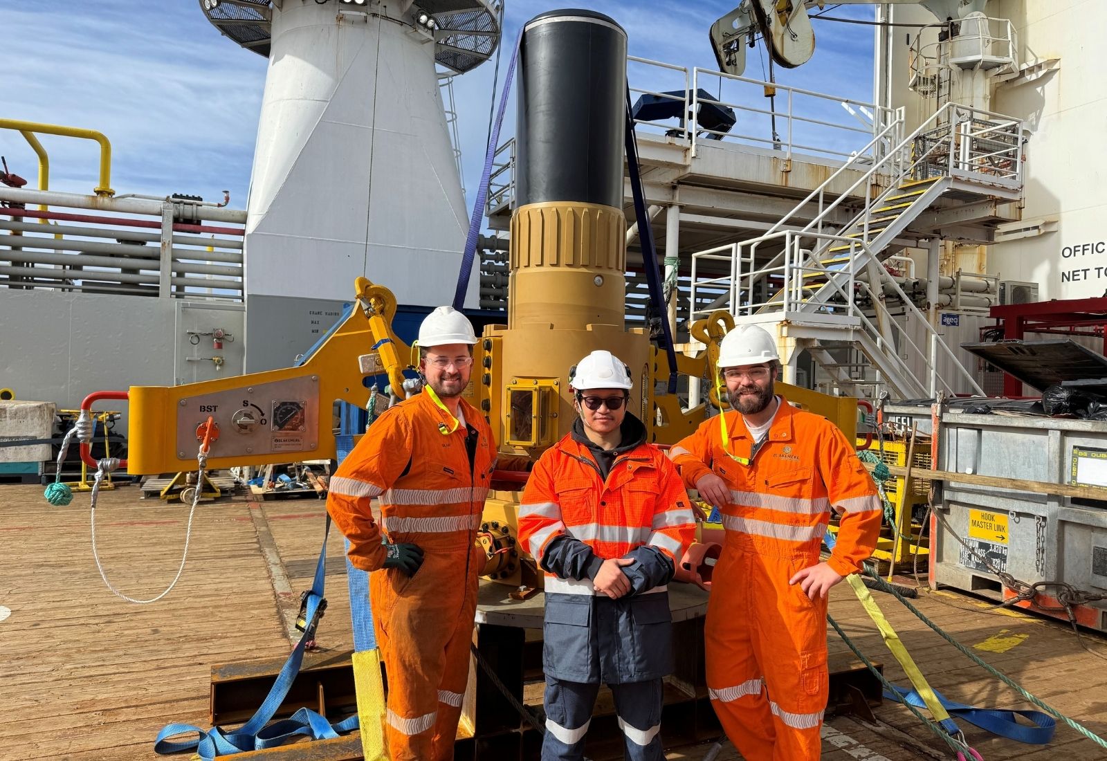Three engineers on a vessel deck in front of a Blakemere subsea intervention tool
