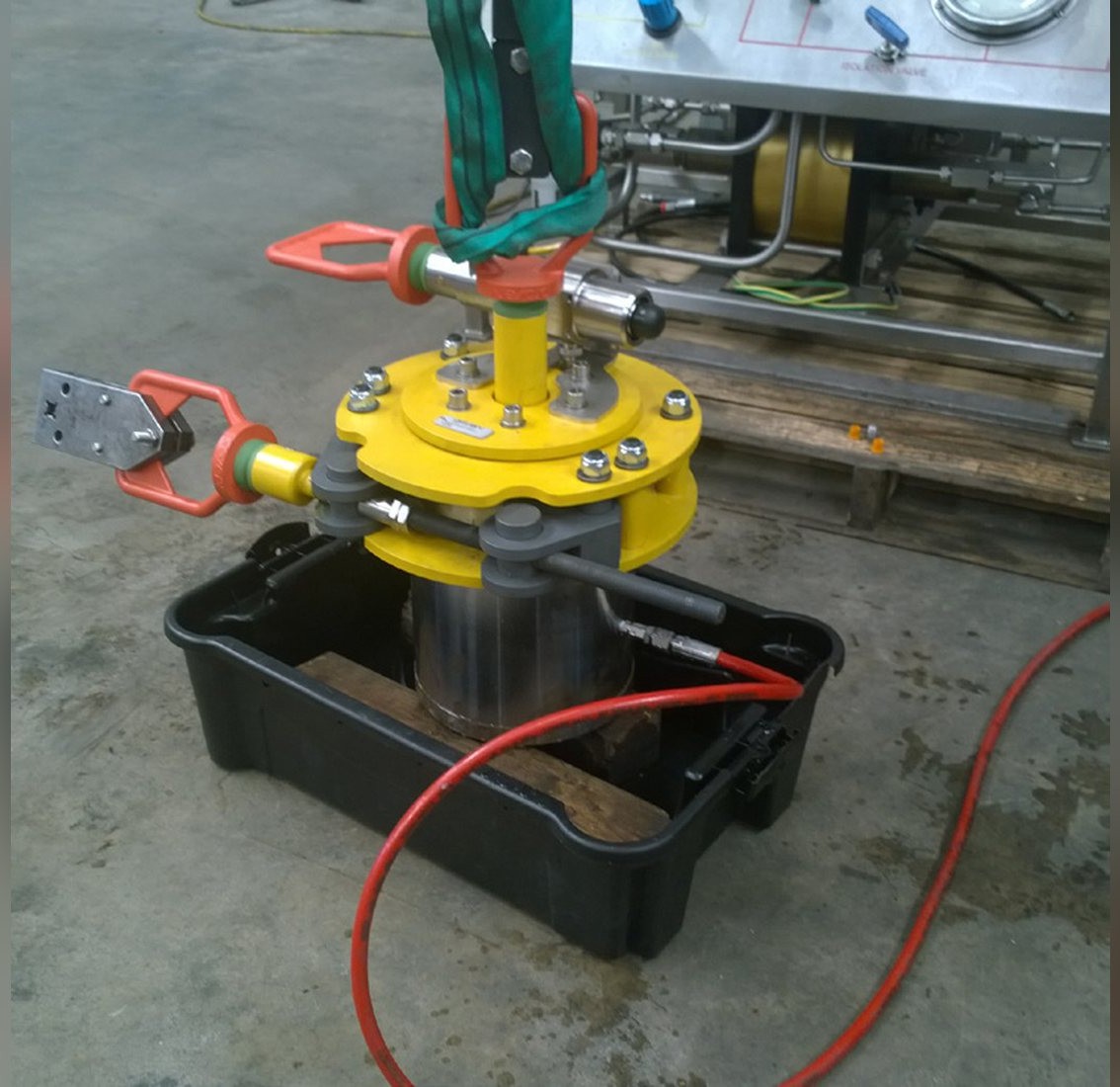 A pressure retaining plug set up on the workshop floor with hydraulic lines connected and a bund tray beneath it, during onshore testing