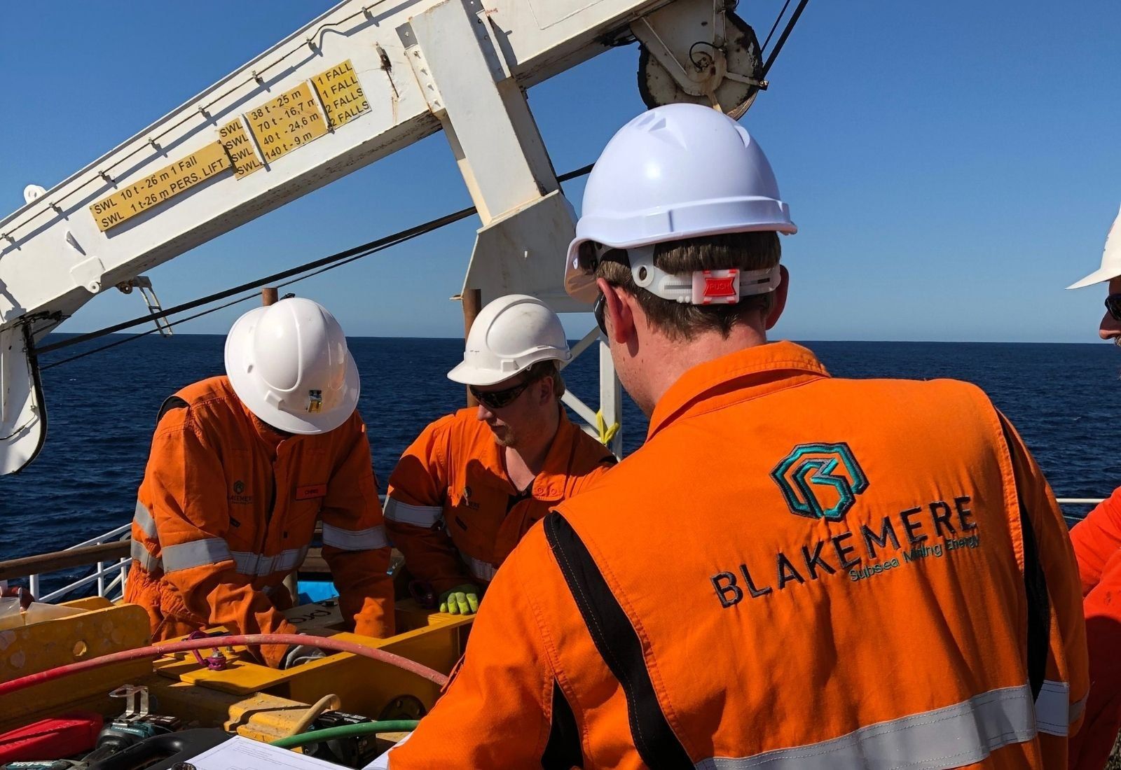 Blakemere engineers conferring over tooling on deck beneath a crane