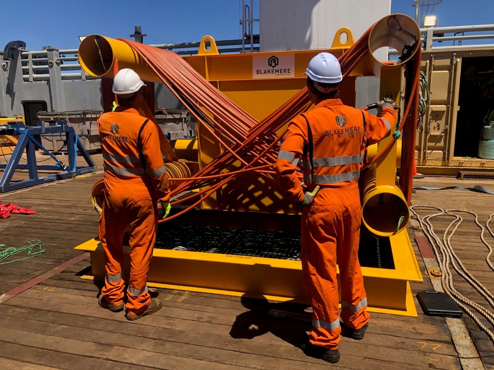 Two Blakemere technicians handling hoses on a Blakemere-branded frame on a vessel deck