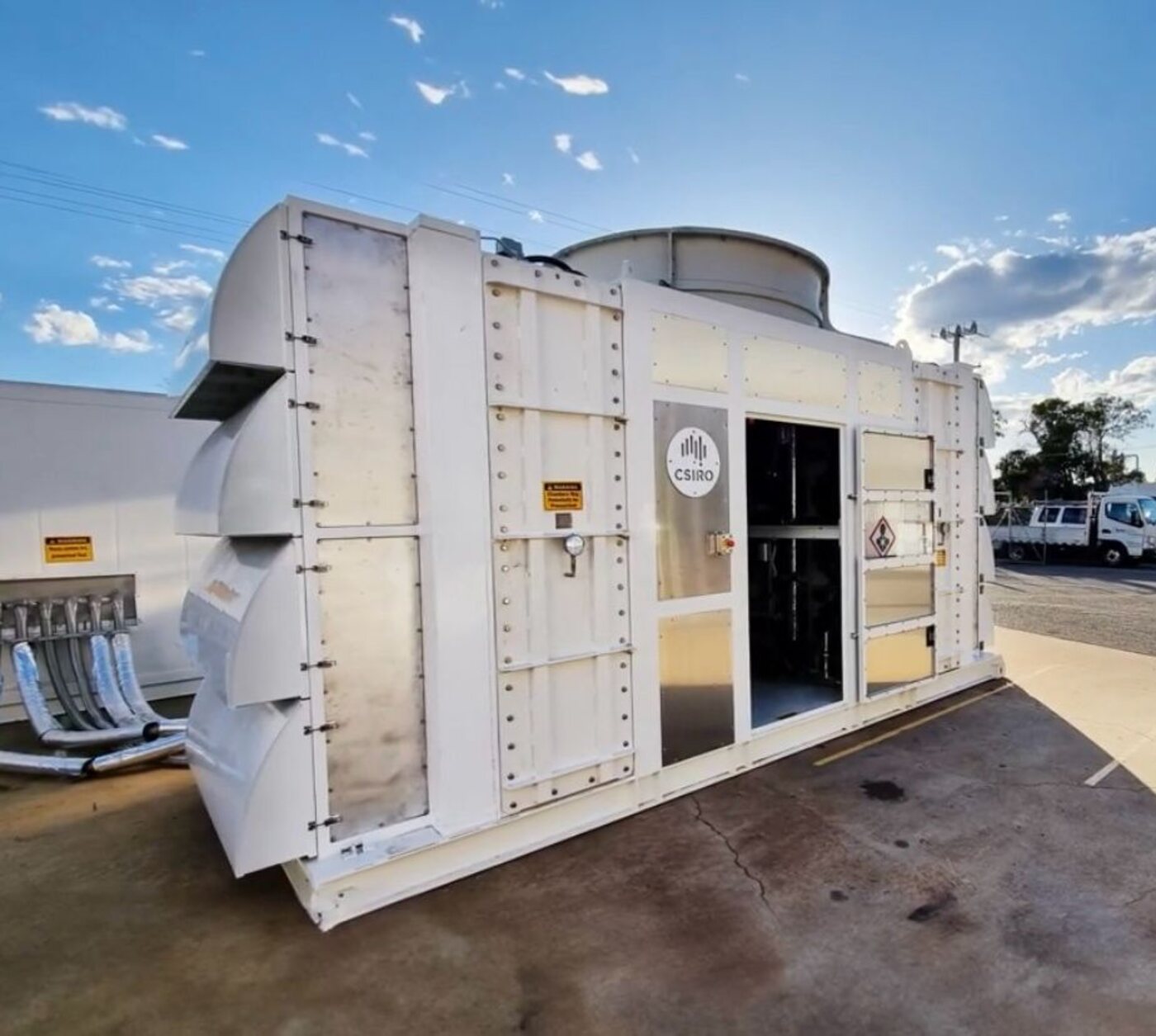 The completed direct air capture prototype standing in the yard, air intake louvres along its flank and the CSIRO mark on the access door