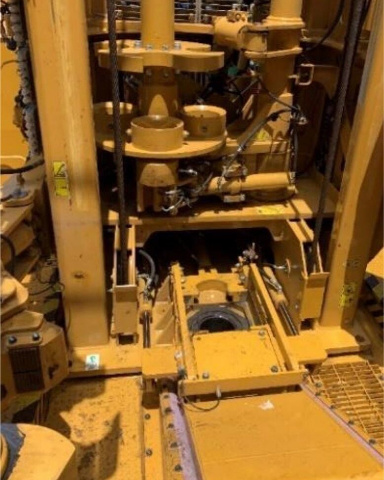Drill floor looking down onto the torque reaction plate, with the mast and drill string above it.