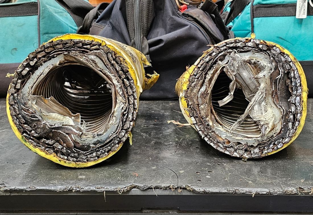 Both ends of a flexible pipe test piece after a single cut by the open bore shear, side by side on a workbench, each bore open and round with its armour layers visible