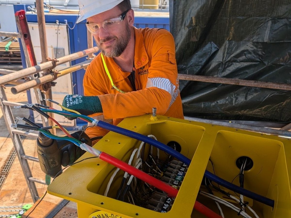 A Blakemere technician terminating cable tails into an open electrical distribution unit housing, with penetrators bolted through the face of the unit