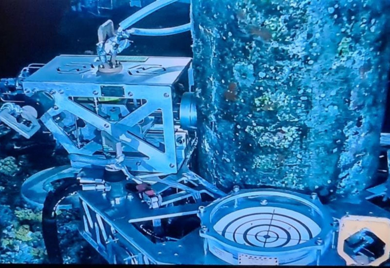Subsea recovery frame landed on a marine-growth covered member, working under ROV lighting