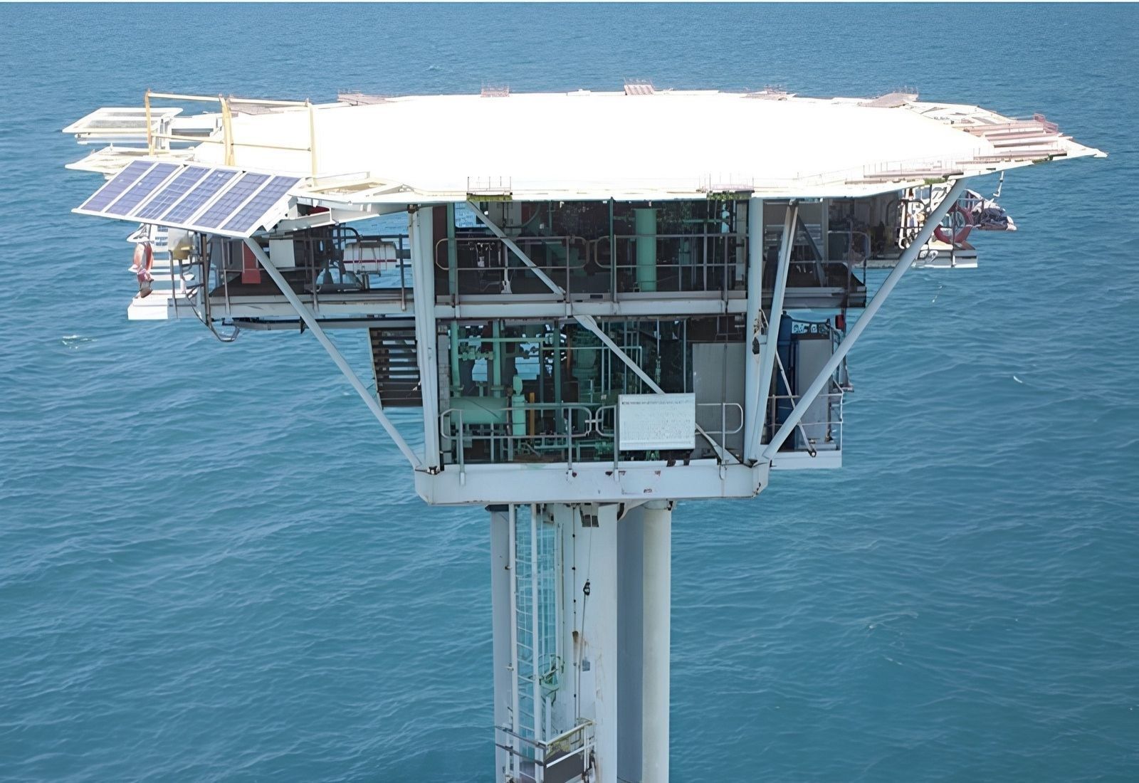 An unmanned monopod platform standing in calm water before removal